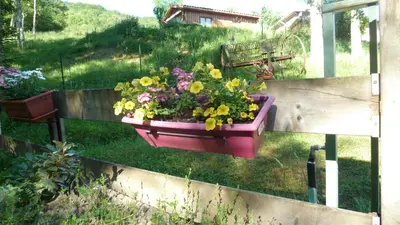 a flower pot with flowers in it hanging on a fence at Gîte la Lanterne transition écologique avec borne de recharge 7kw Site sous vidéo protection in Nalzen