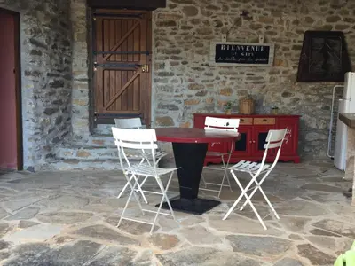 a table and four chairs in a stone room at Le Diable par la queue in Olargues