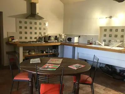 a kitchen with a table and chairs and a counter at Le Diable par la queue in Olargues