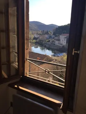 a window with a view of a river and buildings at Le Diable par la queue in Olargues