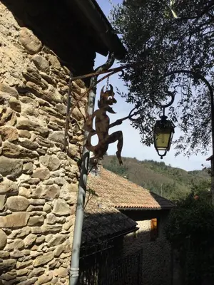 a statue of a cat hanging from a street light at Le Diable par la queue in Olargues