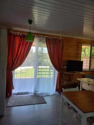 a living room with a large window with red curtains at Chalet 2 pers. + Bébé in Montolieu