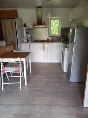 a kitchen with a table and a refrigerator at Chalet 2 pers. + Bébé in Montolieu