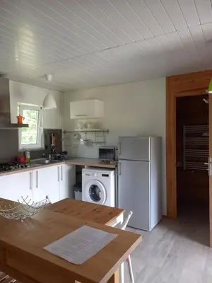 a kitchen with a table and a white refrigerator at Chalet 2 pers. + Bébé in Montolieu