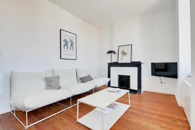 a living room with a white couch and a fireplace at TRIBUS-GITES URBAINS CARCASSONNE in Carcassonne