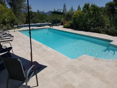 a swimming pool with a chair and an umbrella at Villa w Garden & Guest House in Prades-sur-Vernazobre