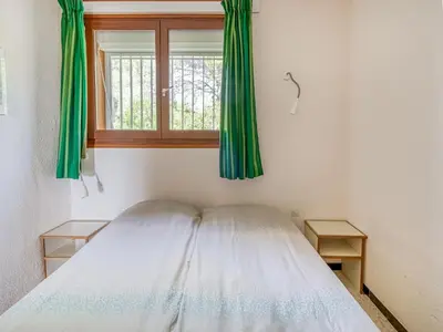 a bedroom with a bed and a window with green curtains at Villa w Garden & Guest House in Prades-sur-Vernazobre