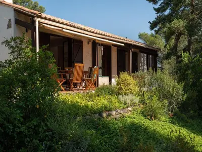 a house with two chairs and a table on the porch at Villa w Garden & Guest House in Prades-sur-Vernazobre