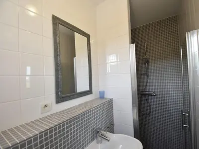 a bathroom with a sink and a mirror and a shower at Villa with heated pool, jacuzzi, sports field and stunning views in Montbrun-des-Corbières