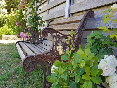 a wooden bench sitting next to a building with flowers at Villa Retreat with Pool and pets in Vélieux