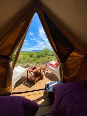 a tent with two white chairs on a wooden deck at Camping la Peiriere - Lodge en Pays Cathare in Tuchan