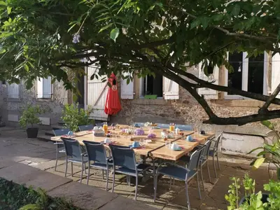 a long wooden table and chairs under a tree at Bastide du Thoré in Labastide-Rouairoux