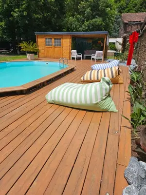 a wooden deck with a swimming pool and two pillows at Bastide du Thoré in Labastide-Rouairoux