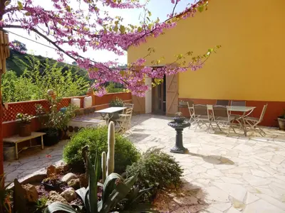 a patio with tables and chairs and a tree with pink flowers at L'Art de Vivre in Latour-de-France