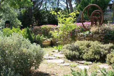 a garden with flowers and a stone wall at Chambres d'hôtes Les Gragniotes in Tournissan