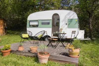 a rv with a table and chairs on a wooden deck at Ma caravane dans les collines in Villeneuve-la-Comptal
