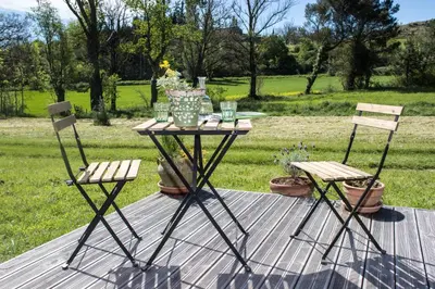 two chairs and a table with a vase on it at Ma caravane dans les collines in Villeneuve-la-Comptal