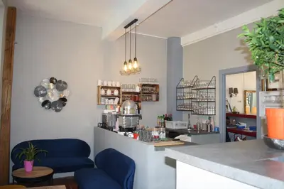 a coffee shop with blue chairs and a counter at Le Therminus chambres d hôtes in Rennes-les-Bains