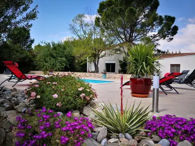 a yard with a pool and some chairs and flowers at Tranquil Villa with Pool in Lézignan-Corbières