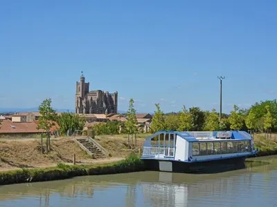 a boat on a river with a castle in the background at Tranquil Villa with Pool in Lézignan-Corbières