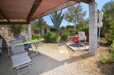 a patio with a table and chairs under a roof at La petite Cigale in Cesseras