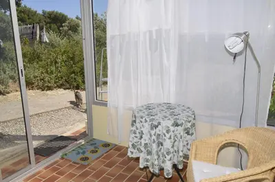 a table sitting on a screened in porch with a window at La petite Cigale in Cesseras