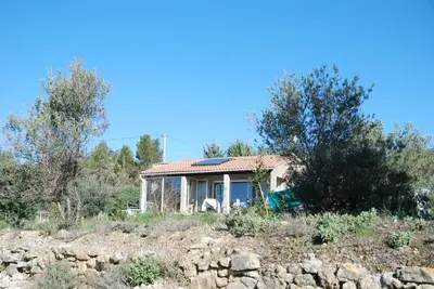 a house on a hill with trees and rocks at La petite Cigale in Cesseras