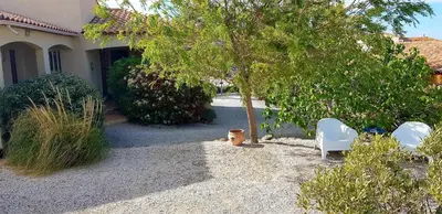 a yard with two chairs and a tree and a house at La villa marquesa in Fitou
