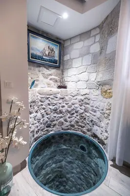a large tub in a bathroom with a stone wall at Chambre du Puits du Couvent in Narbonne
