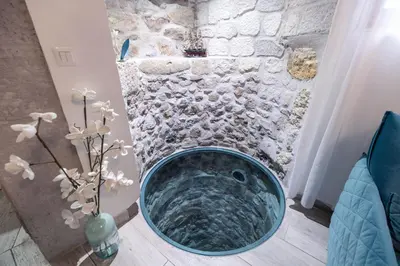 a bathroom with a tub with a stone wall at Chambre du Puits du Couvent in Narbonne