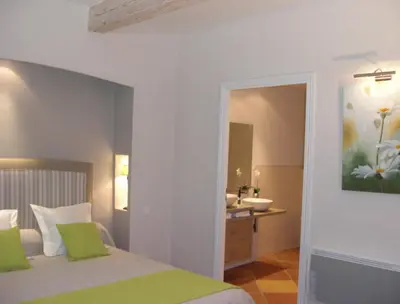 a bedroom with a bed and a bathroom with a sink at Chambres d'Hotes Domaine de la Capelle in Saint-Martin-Lalande