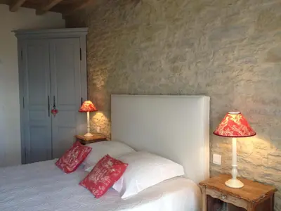 a bedroom with a bed with red pillows and two lamps at Chambres d'Hotes Domaine de la Capelle in Saint-Martin-Lalande