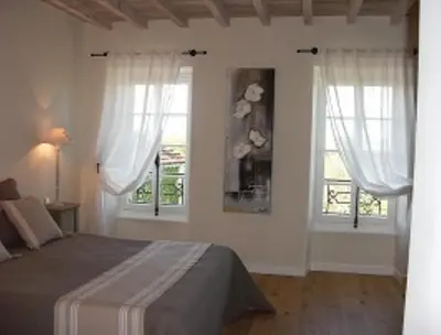 a white bedroom with two windows and a bed at Chambres d'Hotes Domaine de la Capelle in Saint-Martin-Lalande
