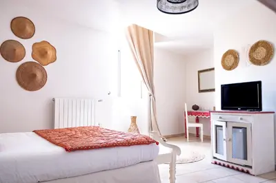 a bedroom with a bed and a tv on a wall at Logis hôtel et restaurant La Bastide Cabezac in Bize-Minervois