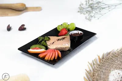 a black plate of food with fruit and vegetables at Logis hôtel et restaurant La Bastide Cabezac in Bize-Minervois
