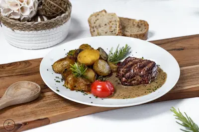 a plate of meat and vegetables on a wooden tray at Logis hôtel et restaurant La Bastide Cabezac in Bize-Minervois