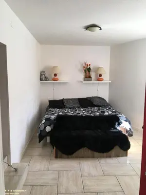 a bedroom with a black bed in a white room at VVA in Conques-sur-Orbiel