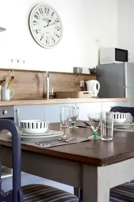 a kitchen with a wooden table with glasses and a clock at Appartements du Vin in Caudiès-de-Fenouillèdes