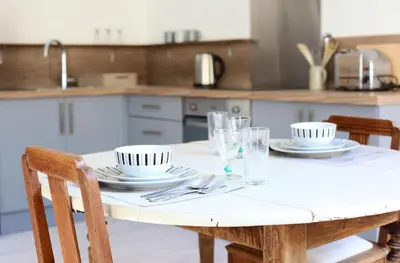 a table with plates and glasses on it in a kitchen at Appartements du Vin in Caudiès-de-Fenouillèdes