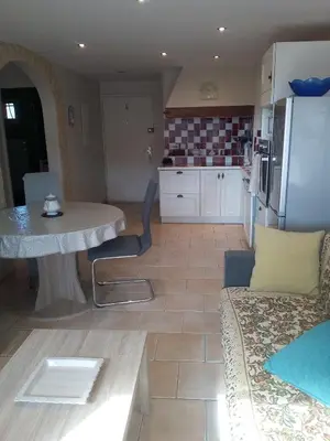 a kitchen and living room with a table and a refrigerator at Appartement en bord de mer in Port-la-Nouvelle