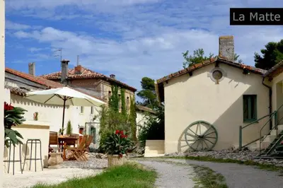 a house with an umbrella and a table and a patio at Domaine de la Matte in Conques-sur-Orbiel