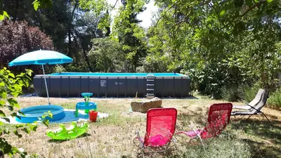 a group of chairs and an umbrella and a pool at Domaine de la Matte in Conques-sur-Orbiel