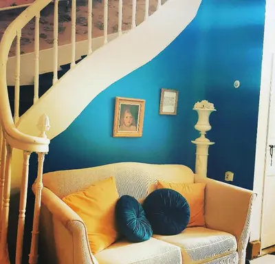 a living room with a couch with blue walls and stairs at B&B Château de Fajac la Selve in Pech-Luna