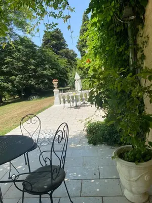 a patio with tables and chairs in a garden at B&B Château de Fajac la Selve in Pech-Luna