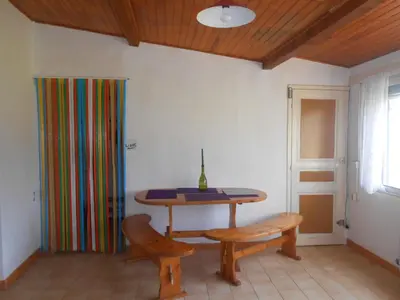 a table and bench in a room with a colorful curtain at Maison Palmeral in Coustaussa