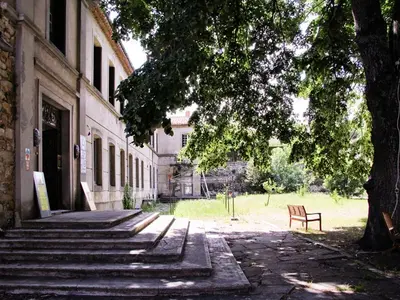 a bench sitting under a tree next to a building at APOSTROPHE Chambres d'Hôtes in Montolieu