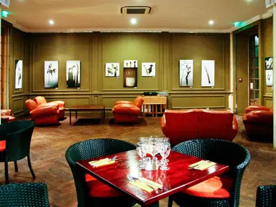 a dining room with a table and chairs and a room with paintings at APOSTROPHE Chambres d'Hôtes in Montolieu