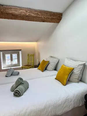 two beds in a room with yellow and gray pillows at LA COUR CARREE - chambres d'hôtes in Carcassonne