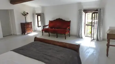 a bedroom with a bed and a red chair at Gites de Montcabirol in Mirepoix