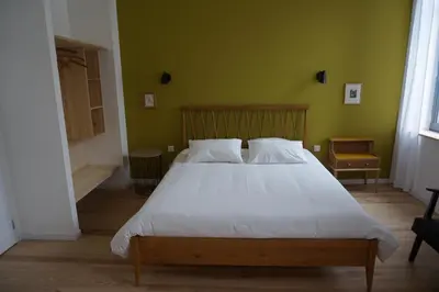 a bedroom with a white bed with a green wall at midi03 in Carcassonne